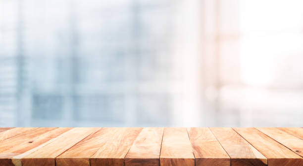 istock Wood table top on blur white glass window background form office building 973364400