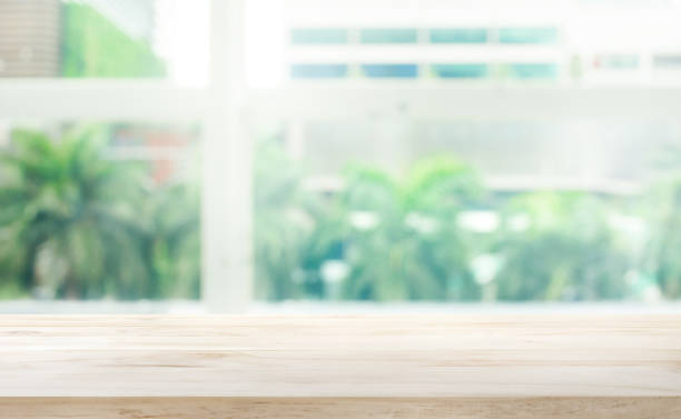 istock Wood table top on blur glass window background 973364420