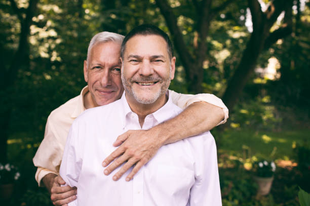 portrait of a loving middle-aged gay couple portrait of a loving middle-aged gay couple surrounded by nature. homosexual couple stock pictures, royalty-free photos & images