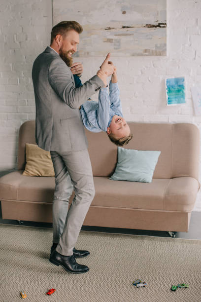 businessman in suit having fun together with little son at home, work and life balance concept businessman in suit having fun together with little son at home, work and life balance concept fashionable dad stock pictures, royalty-free photos & images