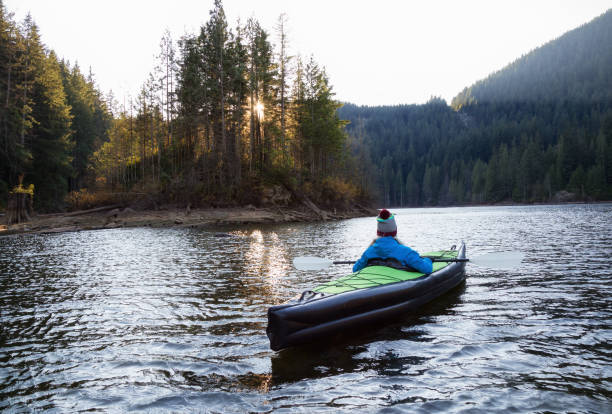 Adventurous girl is kayaking on an inflatable kayak in a beautiful natural lake. Taken in Buntzen Lake, Anmore, Greater Vancouver, BC, Canada.