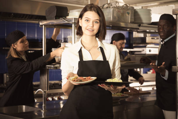 istock Waitress holding meals in restaurant kitchen 973407744