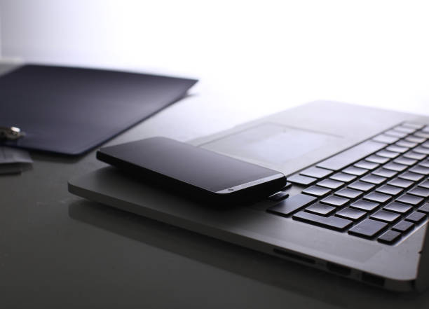 istock Laptop with stack of folders on table on white background 973410732