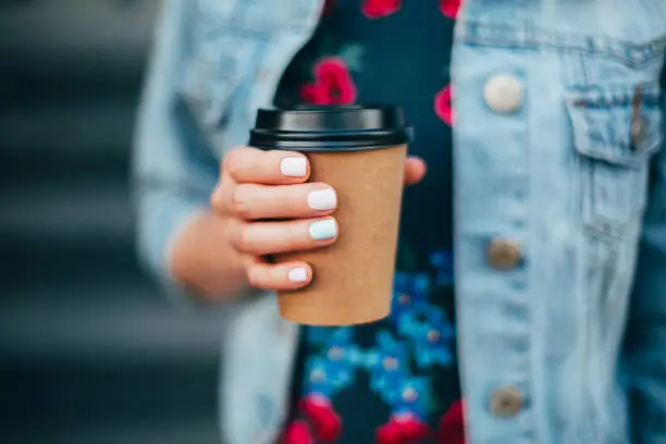 Female hand with paper cup of coffee take away.