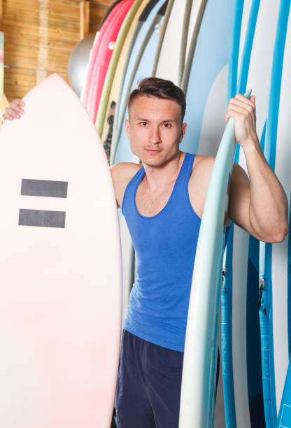 istock Nice man looking for surfboard in surf club 973412028