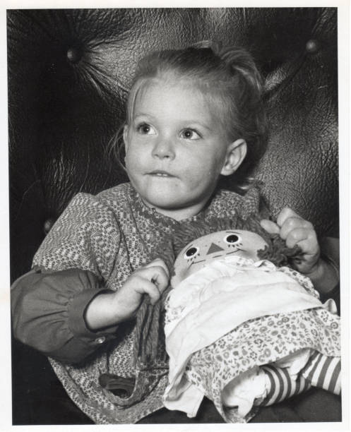 Black and white photograph of a young girl with a doll stock photo