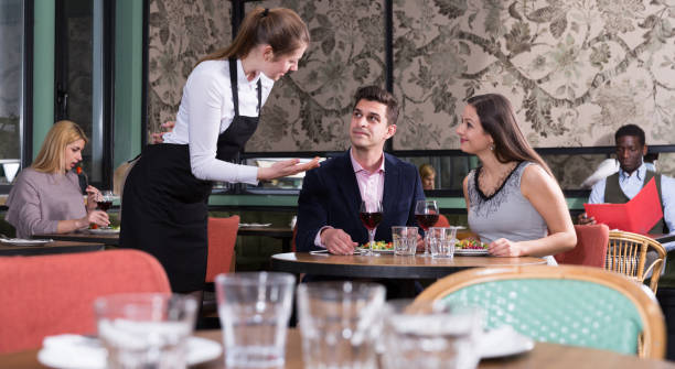 istock Waitress talking with satisfied couple in restaurant 973415266