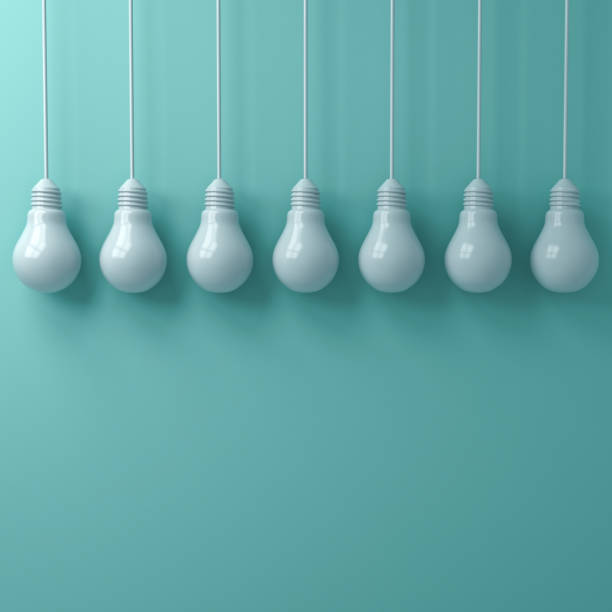istock White hanging light bulbs on green cyan pastel color wall background 3D rendering 973415834