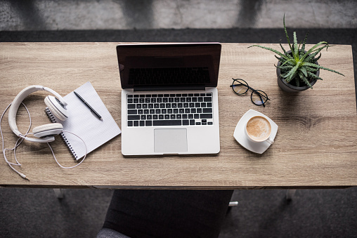 top view of laptop with cup of coffee and headphones at modern workplace