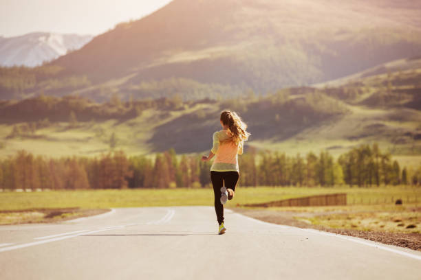 istock Girl is running sunset road mountains 973432520