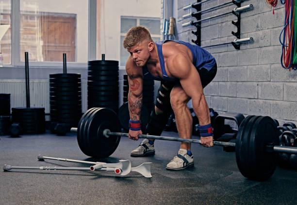 istock Bodybuilder with injured leg holds barbell. 973441780