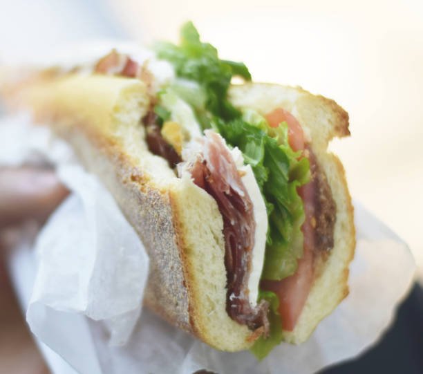 istock Hand holding delicious Italian prosciutto sandwich 973445654