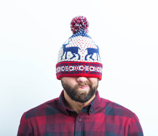 Close up of displeased young beard man in a winter cap on white background