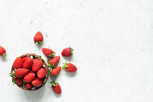 Fresh strawberry in bowl on bright gray concrete background