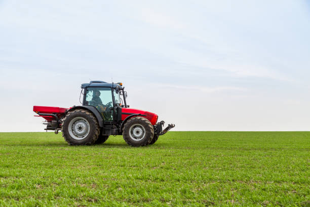 istock Farmer in tractor fertilizing wheat field at spring with npk 973461334