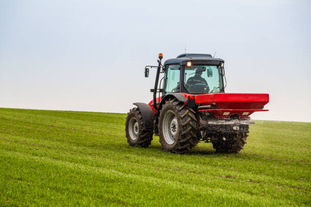 istock Farmer in tractor fertilizing wheat field at spring with npk 973464562