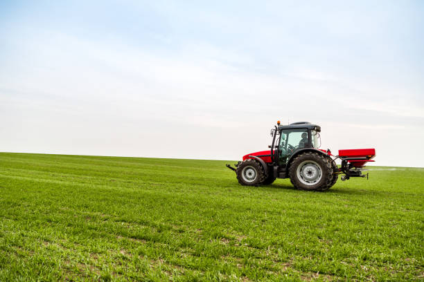 istock Farmer in tractor fertilizing wheat field at spring with npk 973464926