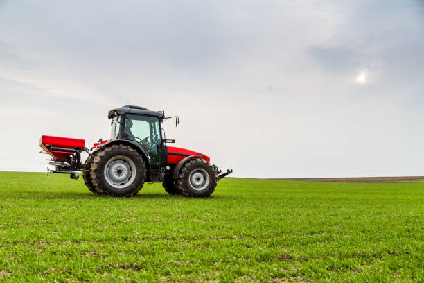istock Farmer in tractor fertilizing wheat field at spring with npk 973465366