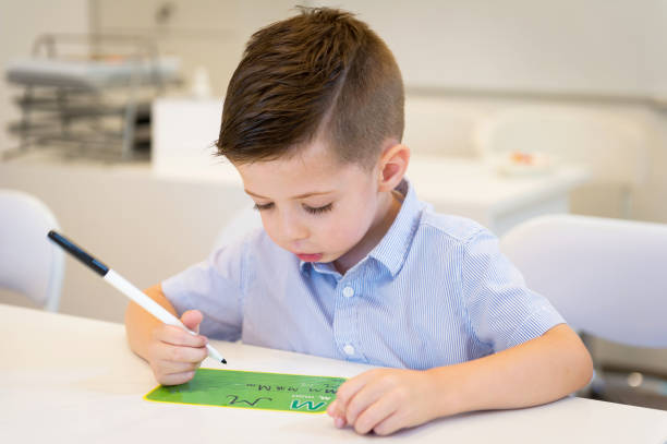 istock preschooler child boy learn to write letter in the classroom 973470174