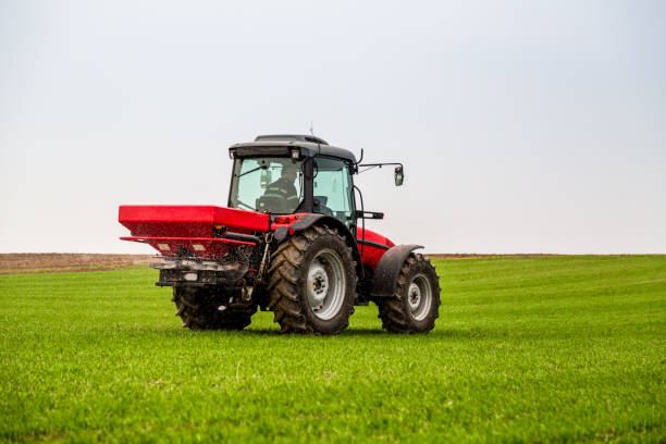 istock Farmer in tractor fertilizing wheat field at spring with npk 973470422
