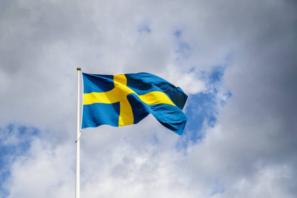 istock Swedish flag with clouds and sky background 973477382