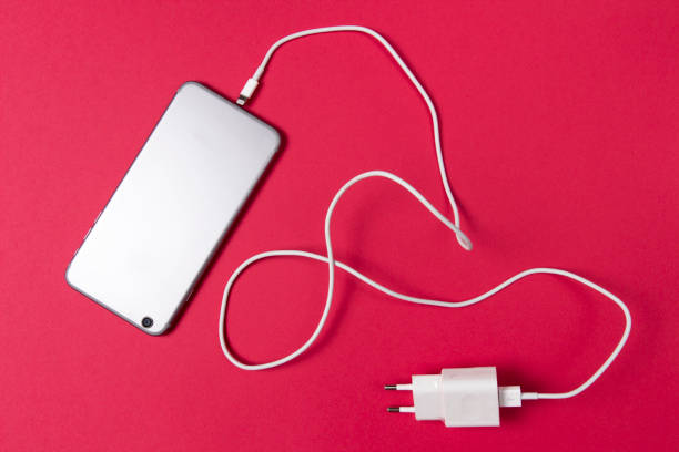 istock modern smartphone and connected charger cable on pink background. 973478058