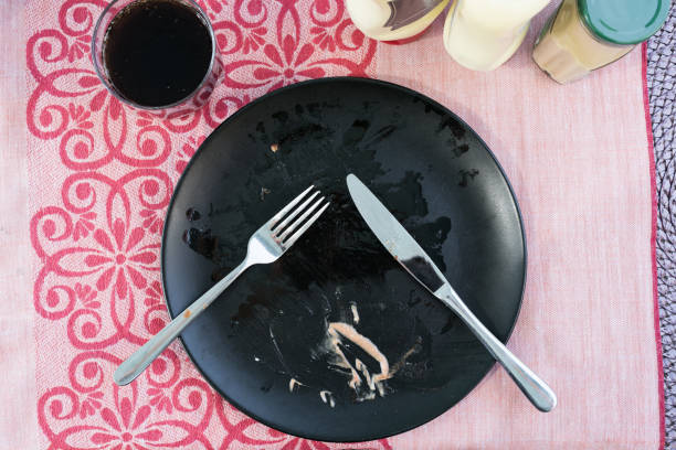 Dirty plate with cutlery and sauces on a table after barbecue dinner.