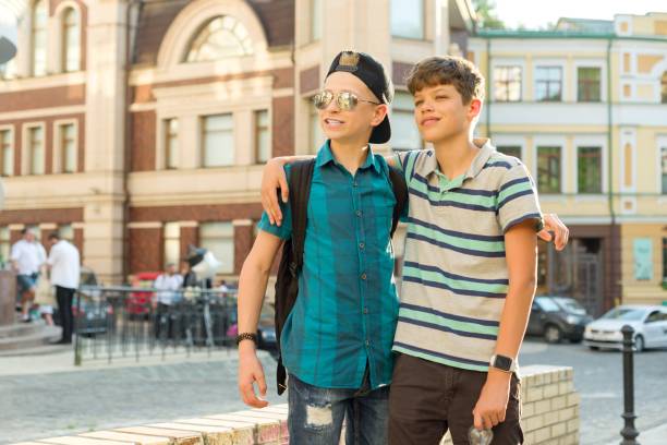 przyjaźń i komunikacja dwóch nastoletnich chłopców ma 13, 14 lat, w tle ulicy miejskiej - friendship early teens 13 14 years city street zdjęcia i obrazy z banku zdjęć