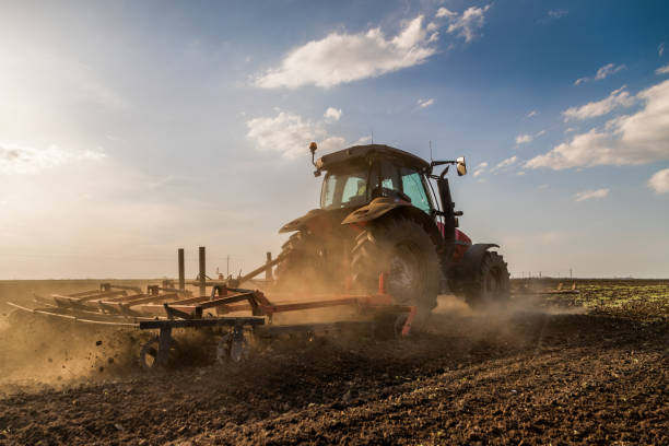 istock Tractor cultivating field at spring 973478638