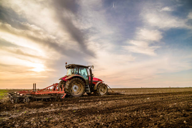 istock Tractor cultivating field at spring 973478770