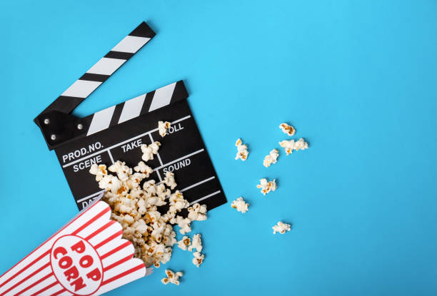 istock Cinema background. Popcorn and clapperboard on blue background 973478792