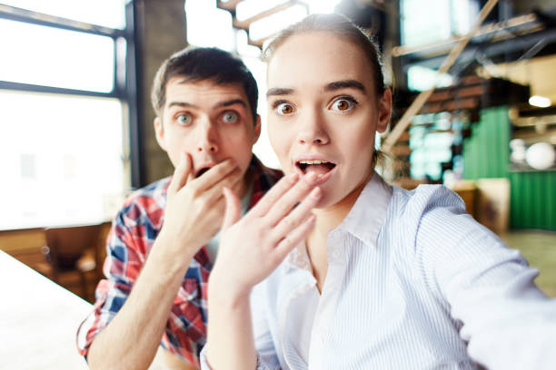 Relaxed cheerful man and girl having fun and making expressive faces at camera taking selfie