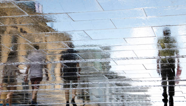 istock Blurry reflection shadow silhouettes of people walking on a rainy spring day 973491976