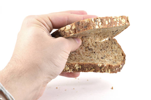 istock Man's hand crushing a slice of whole wheat bread 973498352