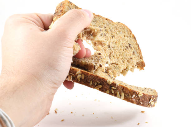 istock Man's hand crushing a slice of whole wheat bread 973498388