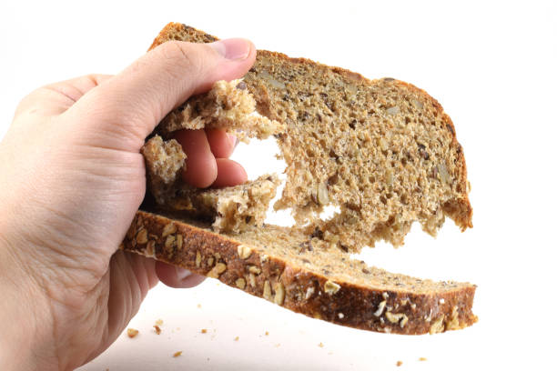 istock Man's hand crushing a slice of whole wheat bread 973498410