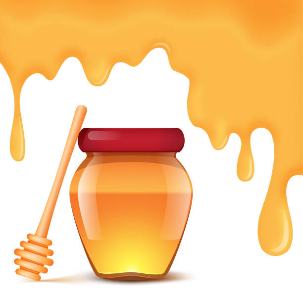 istock A jar of honey and spoon for honey on a white background.  Honey drips background 973501142