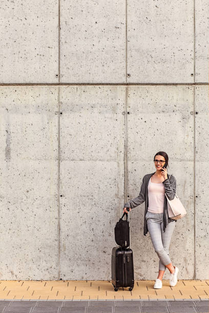 istock Young woman using her smart phone standing beside the concrete wall 973515582