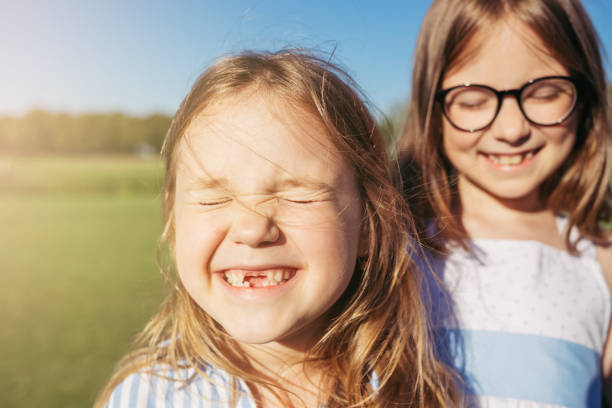 dwie radosne dziewczyny przytulają się i zamykają oczy przed słońcem. - tooth character zdjęcia i obrazy z banku zdjęć