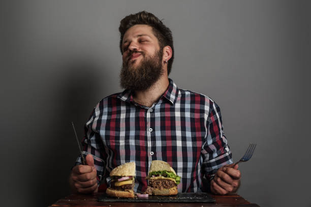man eating burger - burger hamburger large food imagens e fotografias de stock