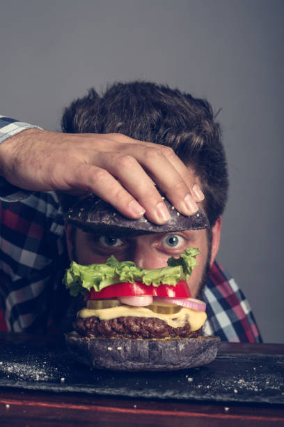 istock Man cooking black burger 973547558