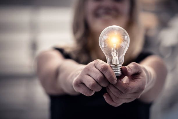 女性手保持電球創造アイデア コンセプト - illusion efficiency light bulb energy ストックフォトと画像