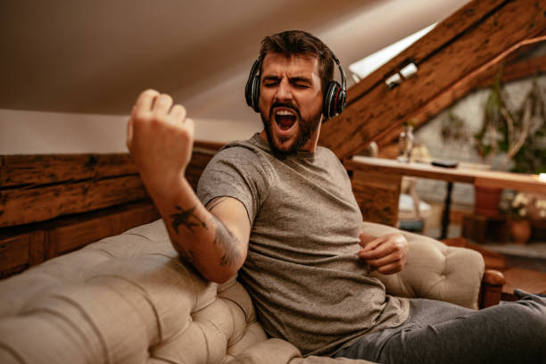 Feeling the music Young man listening to the music and playing imaginary guitar at home air guitar stock pictures, royalty-free photos & images