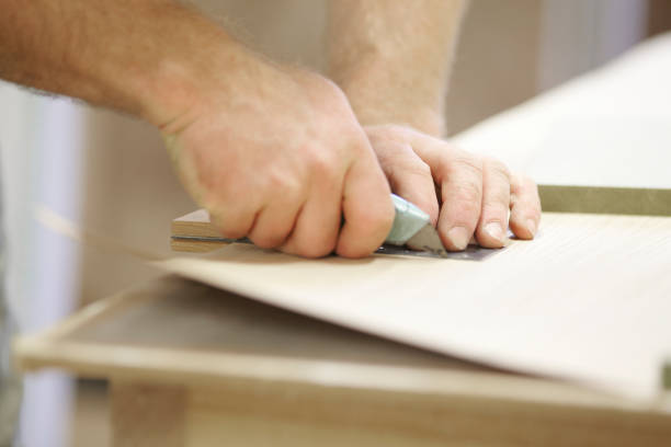 istock Carpenter Adding A Veneer To Wood 973579382