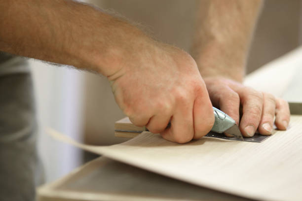 istock Carpenter Adding A Veneer To Wood 973579548