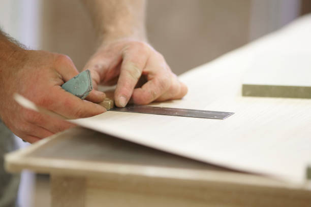 istock Carpenter Adding A Veneer To Wood 973579560