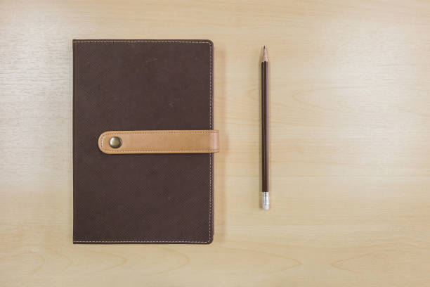 istock Brown note book with pen on wood background 973606886