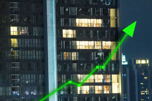 Photo of Stock market bullish activity overnight with highrise window lights showing office people working and trading late night.