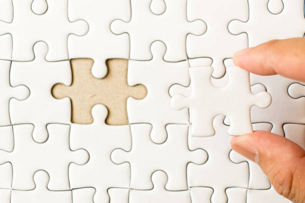 istock Closed up background of white plain jigsaw with hand that hold missing piece to match or fulfill 973636984