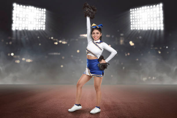 istock Young asian cheerleader action with pom-poms 973649580